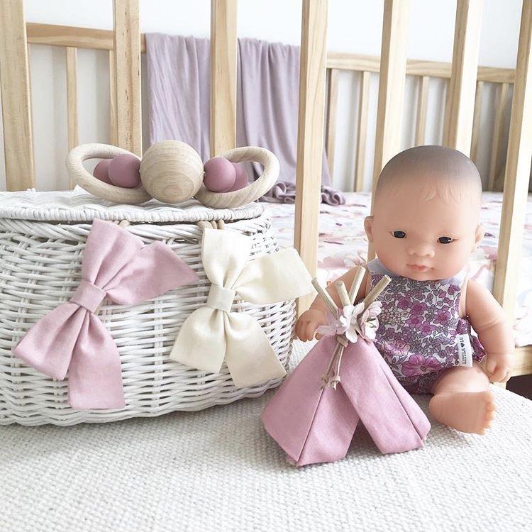 Miniland Asian Baby Doll next to rattan basket